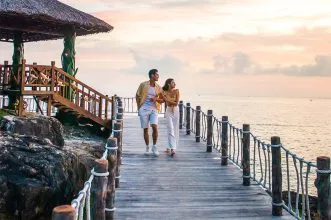 Hình ảnh một cô gái đang mỉm cười và tặng một món quà nhỏ kèm lời chúc kỷ niệm yêu nhau cho người bạn trai, thể hiện sự chu đáo và tình cảm.