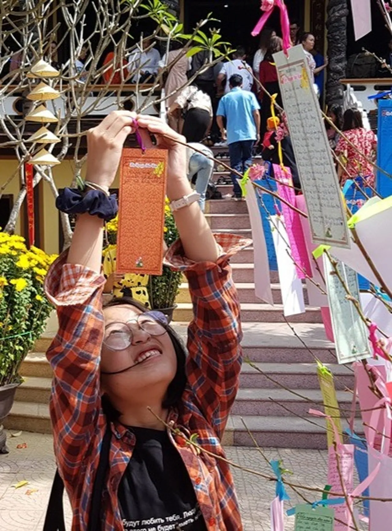 Thiếu nữ thành tâm treo tấm thiệp đỏ chứa đựng tâm nguyện của mình lên cành hoa anh đào