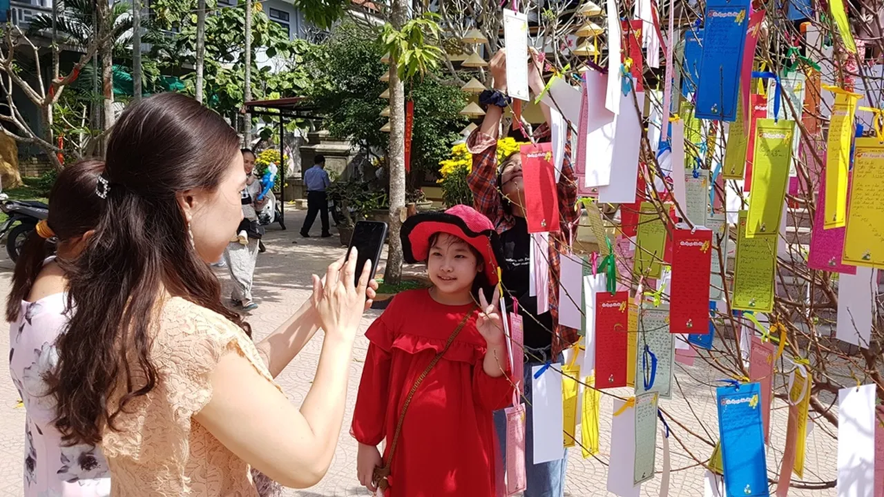 Người mẹ cùng con gái nhỏ lưu lại khoảnh khắc đẹp bên cây cầu nguyện đầy ắp lời chúc đầu năm