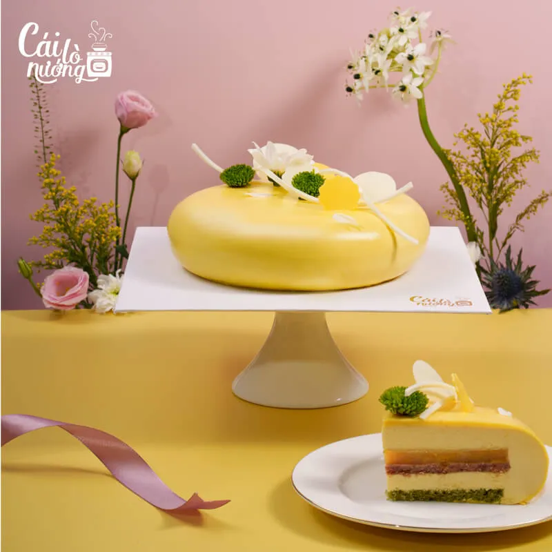 Bánh entremet thanh trà với lớp mousse mịn màng, trang trí hoa tươi và trái cây nhiệt đới