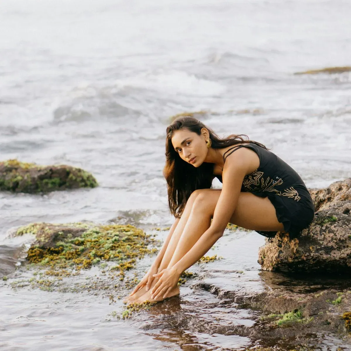 Cô gái ngồi trên mỏm đá bãi biển