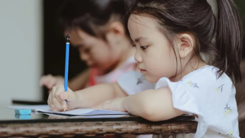 Bé cầm bút làm món quà tặng học sinh